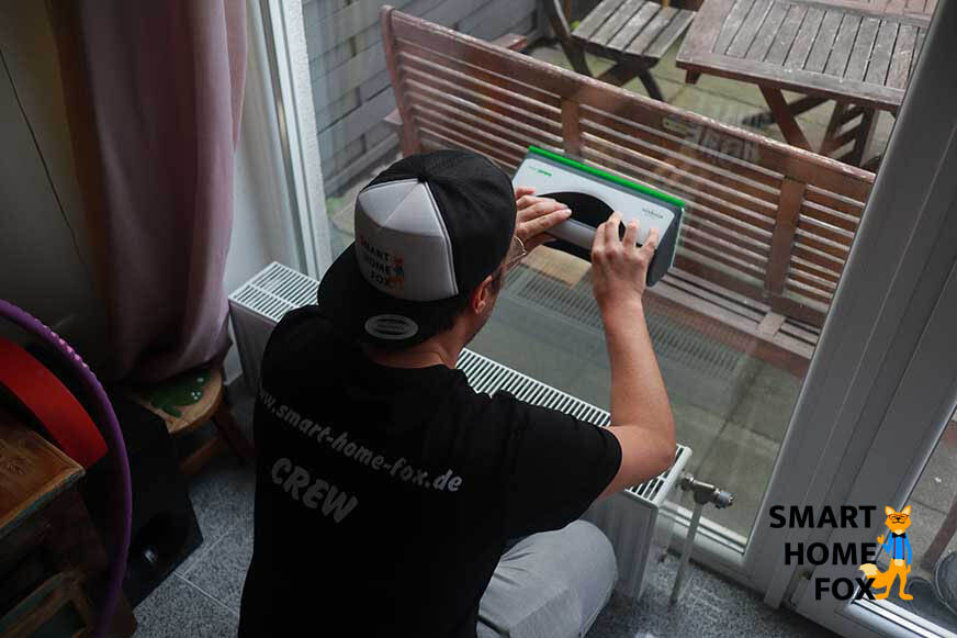 Man sieht, wie eine Scheibe mit dem Vorwerk Kobold VG100 gereinigt wird. 